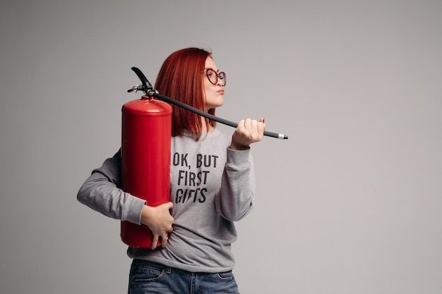 Frau mit roten Haaren in der Hand eines Feuerlöschers