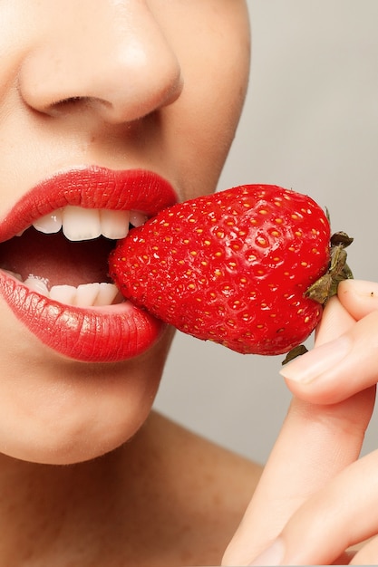 Frau mit roten Lippen, die Erdbeere essen