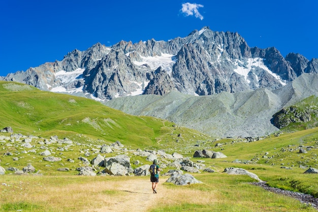 Frau mit Rucksack, der in Richtung Berggipfel, landschaftlich reizvoller Gletscher und dramatische Landschaftssommerfitness wandert