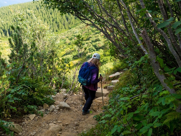 Frau mit Rucksack und Stöcken, die den steilen und extrem schroffen Abstieg von der Spitze des Berges des Chornogora-Kamms in Angriff nehmen Blick in die Nähe des höchsten ukrainischen Karpatenbergs Howerla Ukraine