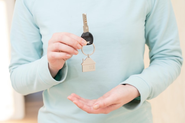 Frau mit Schlüssel mit Schlüsselbund in Form des Hauses