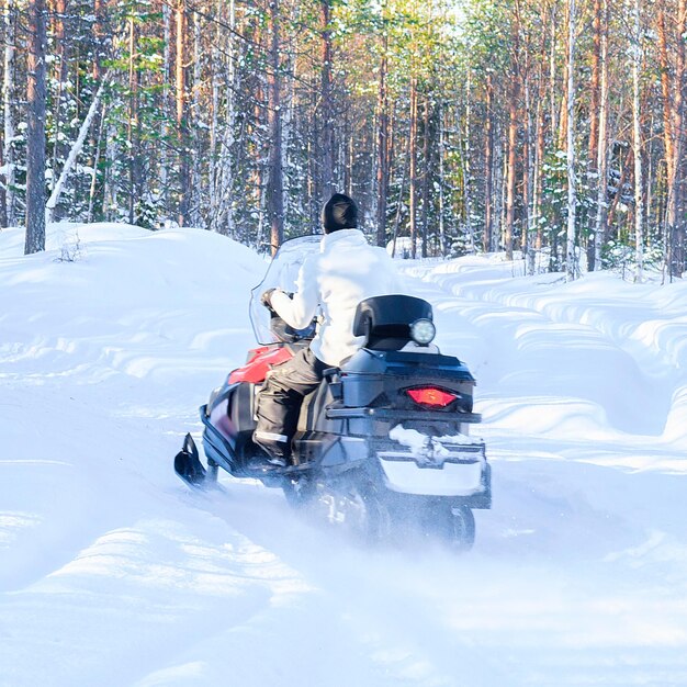 Foto frau mit schneemobil im wald im winter rovaniemi, lappland, finnland