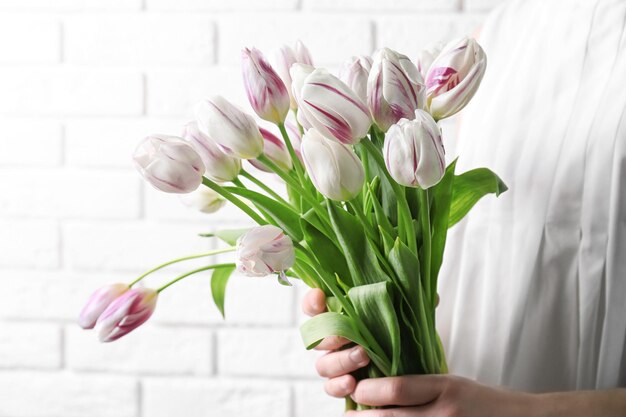 Frau mit schönem Strauß Tulpen auf hellem Hintergrund