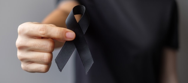 Frau mit schwarzem Band für Melanom und Hautkrebs, Monat des Bewusstseins für Impfverletzungen, Trauer und Ruhe in Frieden. Gesundheitswesen und rassistisches Konzept