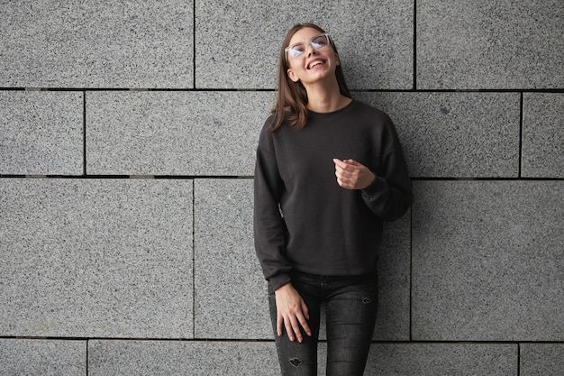 Foto frau mit schwarzem sweatshirt oder hoodie für mock-up, logo-designs oder designdrucke mit freiem platz auf den straßen der stadt.