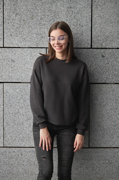 Foto frau mit schwarzem sweatshirt oder hoodie für mock-up, logo-designs oder designdrucke mit freiem platz auf den straßen der stadt.