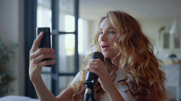 Frau mit Smartphone, die Karaoke singt Sängerin lernt Text eines neuen Liedes