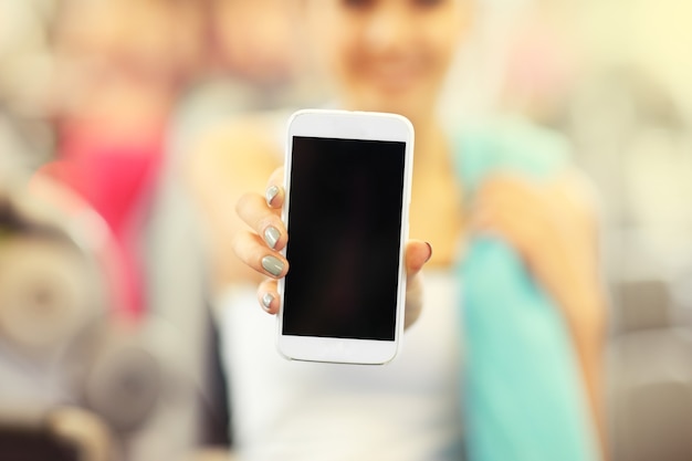 Frau mit Smartphone im Fitnessstudio