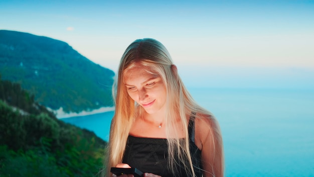 Foto frau mit smartphone mit meer im hintergrund urlaub in warmen ländern