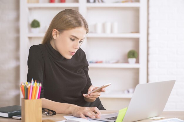 Frau mit Smartphone und Laptop