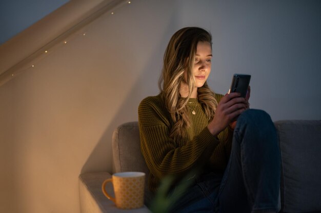 Frau mit Smartphone, während sie zu Hause auf dem Sofa sitzt