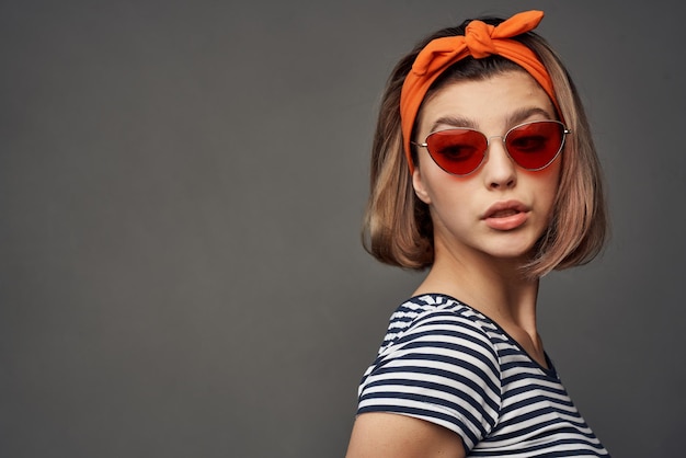 Frau mit Sonnenbrille mit orangefarbenem Verband auf dem Kopf isolierte Hintergrundmode