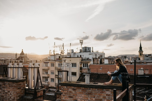 Foto frau mit sonnenbrille sitzt auf einer stützmauer in der stadt