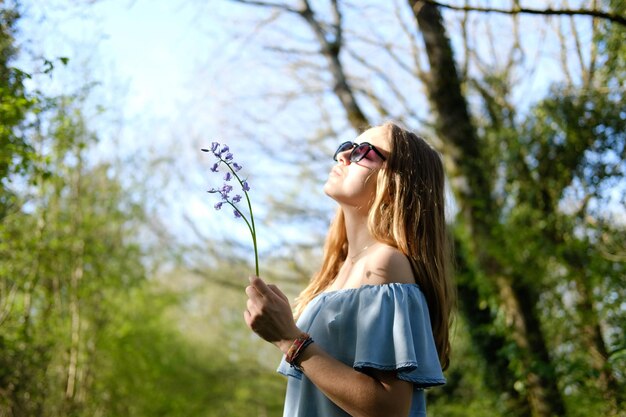 Frau mit Sonnenbrille steht gegen Pflanzen