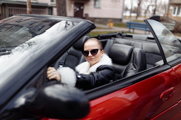 Frau mit sonnenbrille und pelzmantel in einem cabrio