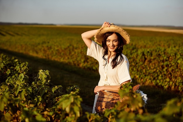 Frau mit Strohhut, der Weidenkorb hält und auf Feld steht.