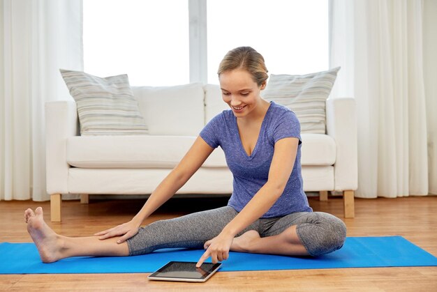Frau mit Tablet-Computer macht Yoga zu Hause
