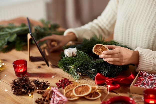 Frau mit Tablet-PC macht Weihnachtskranz
