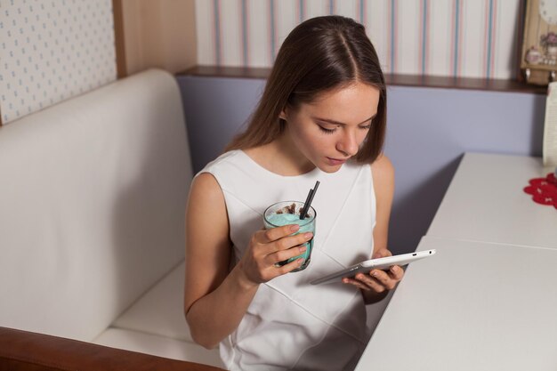 Frau mit Tablet und Getränk im Café