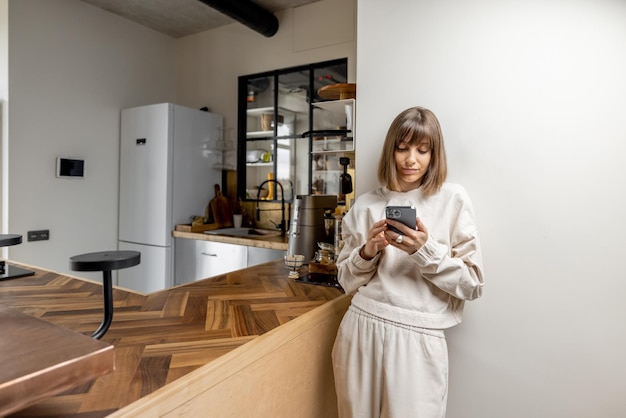 Frau mit Telefon an moderner Küche