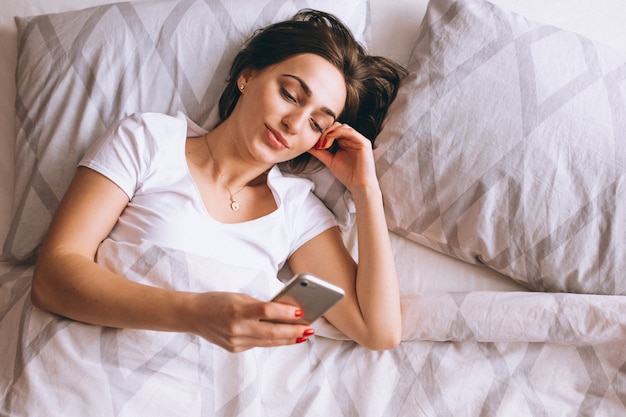 Frau mit Telefon im Bett