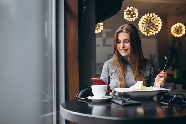 Frau mit Telefon Salat in einem Café essend