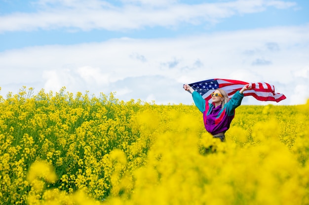 Frau mit USA-Flagge im gelben Rapsfeld