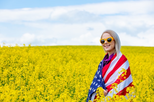 Frau mit USA-Flagge im gelben Rapsfeld