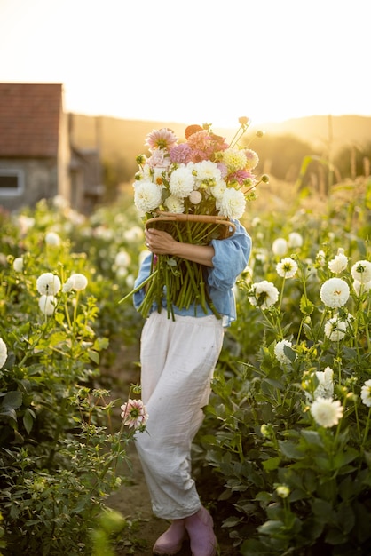 Frau mit vielen Blumen auf Dahlienfarm im Freien