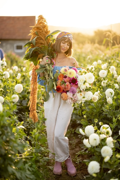 Frau mit vielen Blumen auf Dahlienfarm im Freien