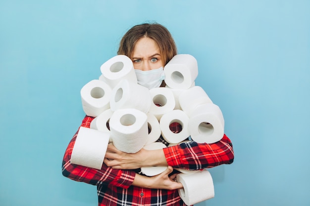 Frau mit vielen Rollen Toilettenpapier in den Händen. Mangel an Toilettenpapier während der Coronavirus-Pandemie. Mangel an Hygieneprodukten.