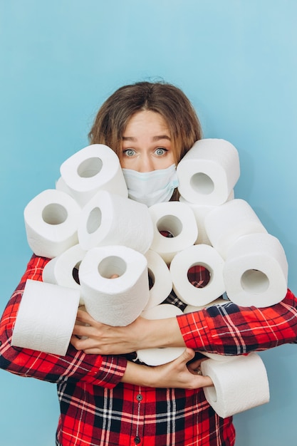 Frau mit vielen Rollen Toilettenpapier in den Händen. Mangel an Toilettenpapier während der Coronavirus-Pandemie. Mangel an Hygieneprodukten.