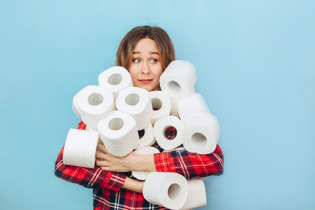 Frau mit vielen Rollen Toilettenpapier in den Händen. Mangel an Toilettenpapier während der Coronavirus-Pandemie. Mangel an Hygieneprodukten.