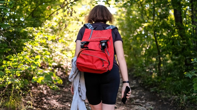 Frau mit Wanderrucksack auf einem Waldweg