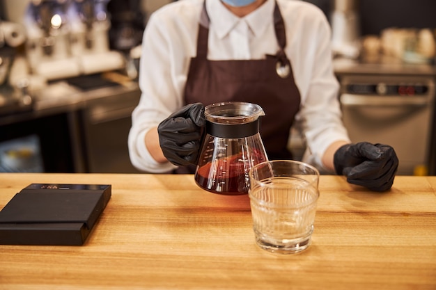 Frau mit wasserkocher mit kaffee oder tee in der nähe des glases