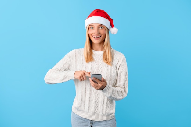 Frau mit Weihnachtsmütze sms't am Telefon