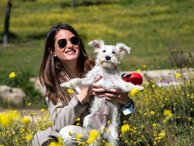 Frau mit weißem Schnauzerhund im gelben Blumenfeld