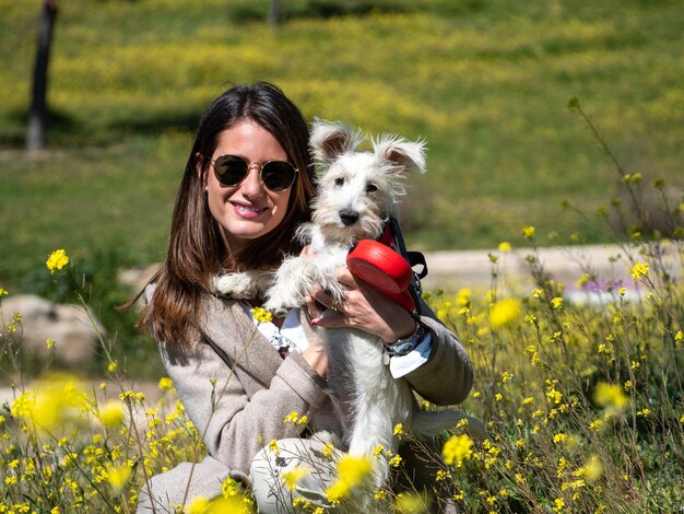 Frau mit weißem Schnauzerhund im gelben Blumenfeld