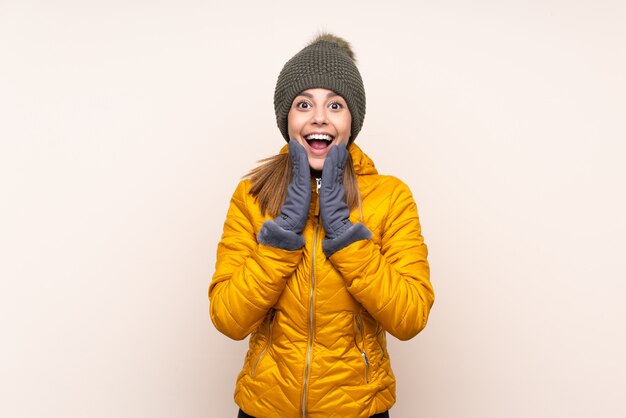 Frau mit Wintermütze über isolierter Wand mit Überraschungsgesichtsausdruck