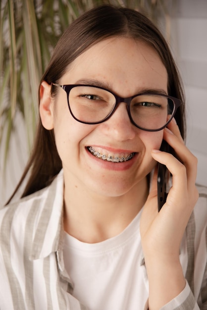 Foto frau mit zahnspange in brille spricht und löst das problem mit dem smartphone im haus