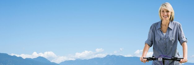 Frau mittleren Alters auf dem Fahrrad gegen Berggipfel und Himmel