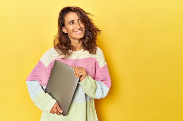 Frau mittleren Alters benutzt Laptop auf Gelb