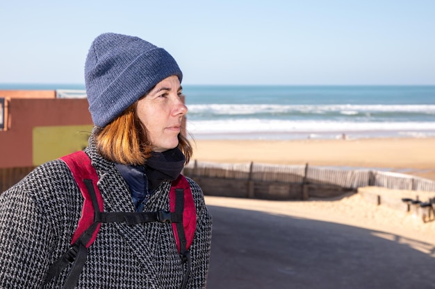 Frau mittleren Alters, die am Wintertag im Freien an der Strandküste spazieren geht