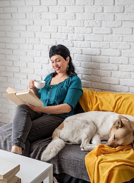 Frau mittleren Alters, die auf der Couch liest