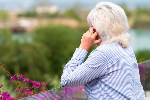 Frau mittleren Alters, die auf einer Außenterrasse mit ihrem Telefon chattet