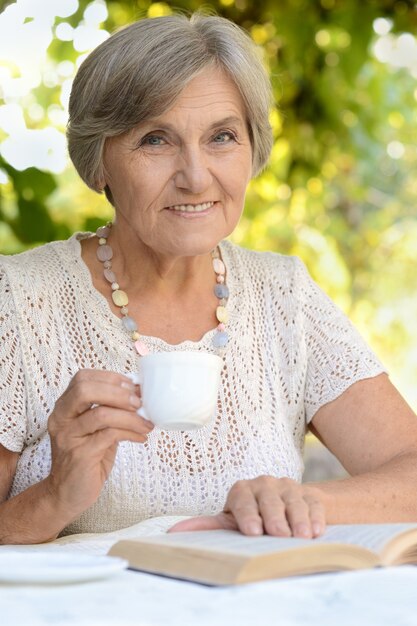 Frau mittleren Alters, die ein Buch liest und Tee trinkt