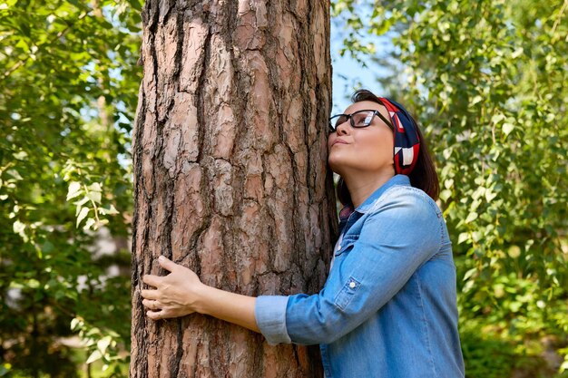 Frau mittleren Alters, die eine Baumenergie der Natur umarmt