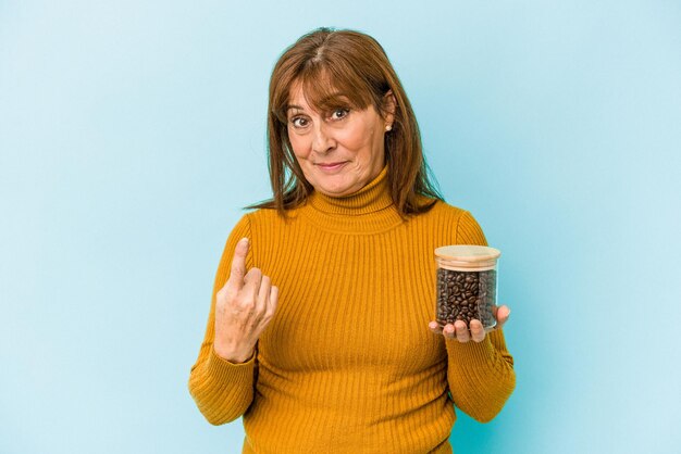 Frau mittleren Alters, die eine Kaffeedose auf blauem Hintergrund hält