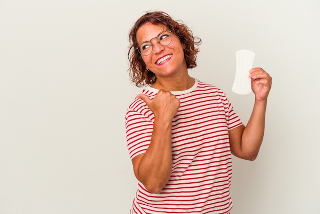 Frau mittleren Alters, die eine Kompresse isoliert auf weißem Hintergrund hält, zeigt mit dem Daumenfinger weg, lacht und sorglos.