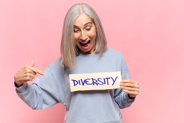 Frau mittleren Alters, die eine Notiz mit dem Text hält: Vielfalt